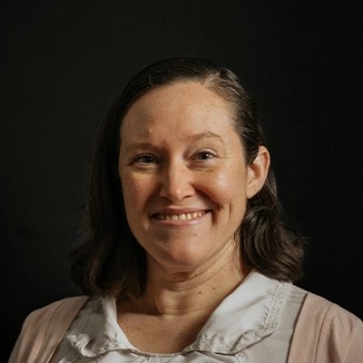 Massage Therapist Kymberly Spooner Smiling In Front Of Dark Background