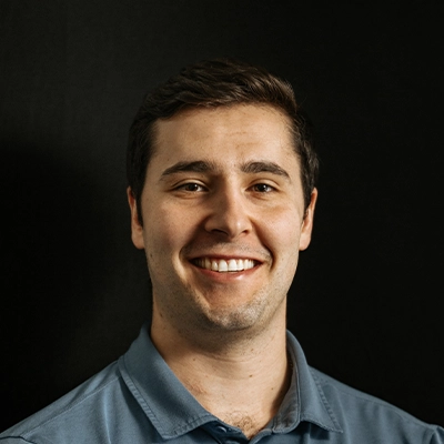Chiropractor Adam Mitola About Smiling In Front Of Dark Background