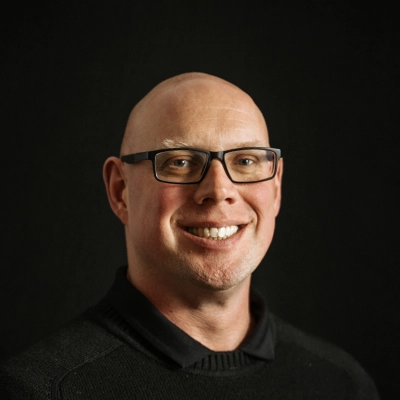 Chiropractor Luke Dijkstra About Smiling In Front Of Dark Background